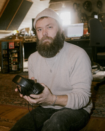 Portræt af Blacksmith-musiker Thomas Alstrup i musikstudie med høretelefoner i hænderne. 