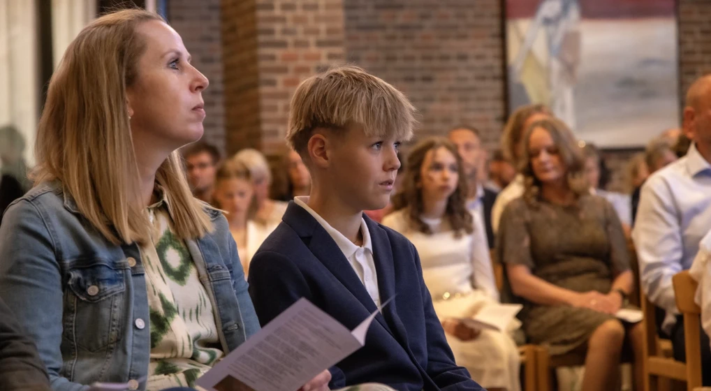 Dreng sidder på sin særlige plads i midtergangen under konfirmationen.