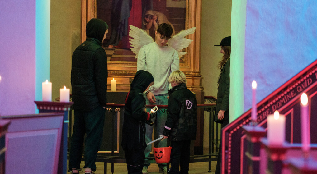 Konfirmand klædt ud som engel uddeler slik til børn i Blovstrød kirke